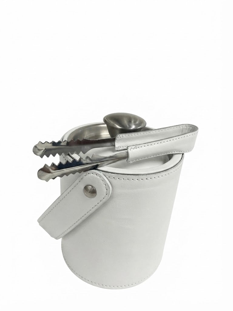 A white premium leather cylindrical ice bucket with a matching handle and snap closure, holding a stainless steel ice scoop and metal tongs, on a plain white background.