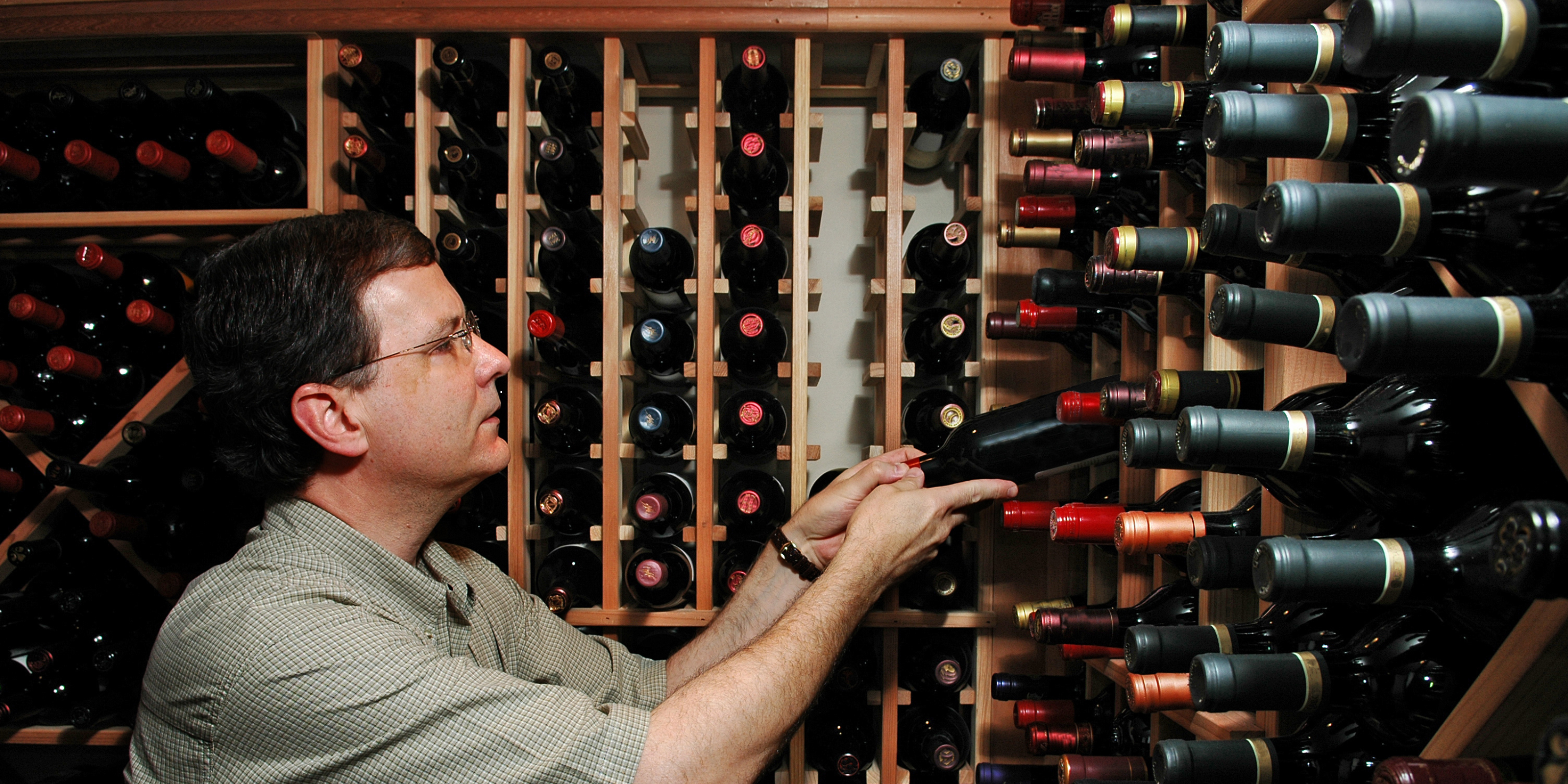 Biggest range of wine racks in Australia examining wine bottles in a wine cellar
